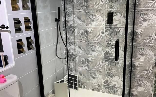 11 - Matt Black, Pivot Door Shower Enclosure beside decorative Wall Panels in Croxley Plumbing Supplies Bathroom Showroom at Croxley Green, Rickmansworth