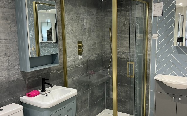 12 - Brushed Gold Sliding Door Shower Enclosure besides a Vanity Unit & Mirrored Cabinet in Croxley Plumbing Supplies Bathroom Showroom at Croxley Green, Rickmansworth
